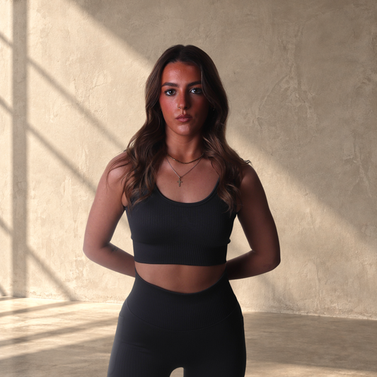 Model wearing a black Lanula ribbed seamless sports bra with a sculpted fit against a white background.