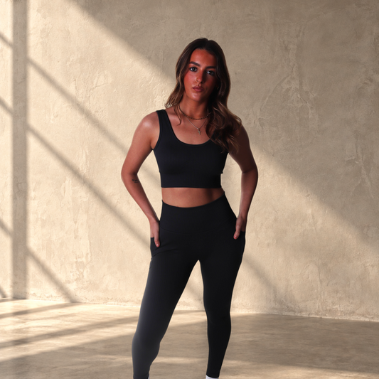 Model wearing a black Lanula ribbed seamless bra and high-rise leggings set with a sculpted, textured fit.