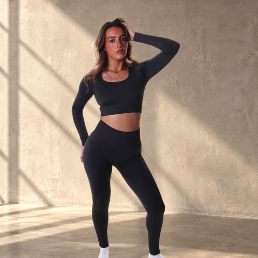 Model wearing Lanula black ribbed seamless high-rise leggings and matching long-sleeve crop top against white background