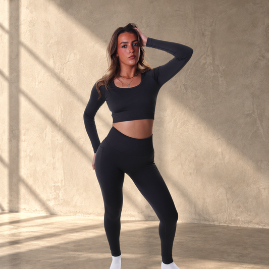 Model wearing a Lanula black long-sleeve ribbed seamless crop top and matching leggings against a white background.