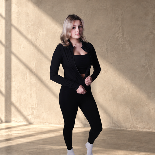 A model wearing Lanula black high-rise running leggings and a matching zip-up performance jacket.