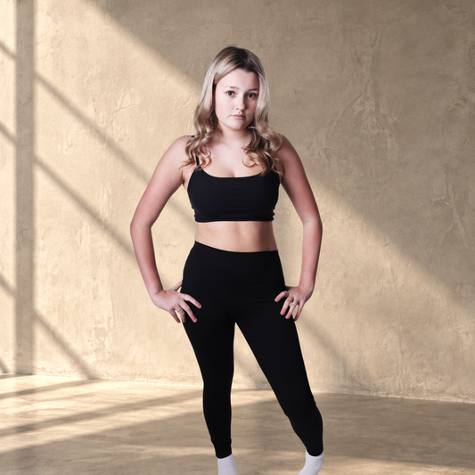Model wearing a black Lanula Core Bra and matching leggings, featuring a sculpted fit for studio and everyday wear.