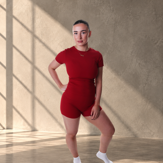 Model wearing a red Lanula Studio Top and matching shorts in a smooth, supportive stretch fabric for studio workouts.