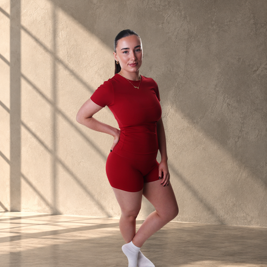 Model wearing red Lanula Studio Shorts with a matching high-rise waistband and sculpting stretch fabric